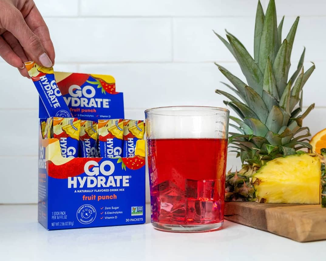 GoHydrateFruit Punch - Open box with a pineapple on a cutting board and a clear glass with red liquid