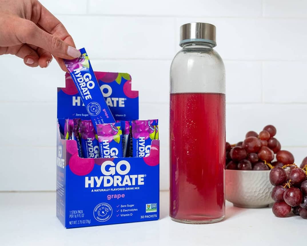 GoHydrate Grape - open box with a clear water bottle with purple liquid and purple grapes in a bowl